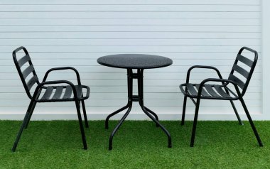 Bahçe bahçesinde siyah sandalyeler ve masa