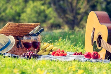 Kırmızı şarap, bardak, şişe, piknik sepeti, gitar ve yemek hazır.
