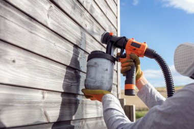 Painting fence or garden shed with a paint sprayer, home diy maintenance clipart