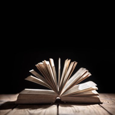 Eski kitap ya da açık İncil okuma, hikaye anlatma ve eğitim için spot ışık kavramına sahip bir masada veya İncil ve din, metin veya kopya için yukarıdaki siyah arka plan alanı