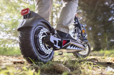 Elektrikli scooter ya da kırsal alanda yaz güneşinde bir orman yolunda e-scooter taşımacılığı