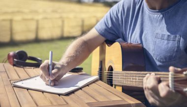Müzisyen gitarist söz yazarı akustik gitar çalıyor ve müzik yazıyor.