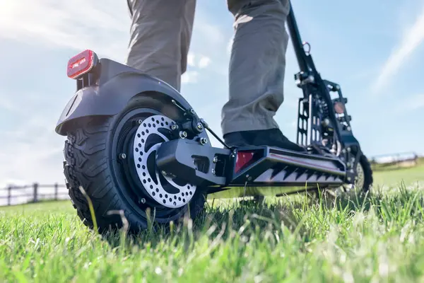 Elektrikli scooter ya da kırsal kesimde e-scooter taşımacılığı yaz güneşinde çimlerin üzerinde çim üzerinde.