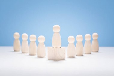 Liderlik konsepti, ahşap iş takımı ve bir kişi podyumda kalabalığın arasından öne çıkıyor.