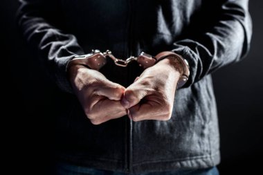 Elleri kelepçeli, elleri kelepçeli tutuklu bir adam hapiste.