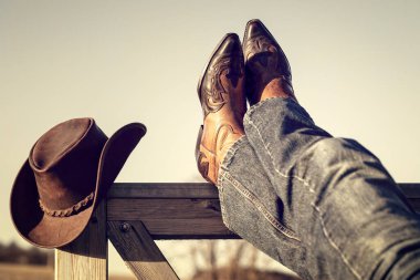 Kovboy çizmeleri ve ayakları ahırın kapısında bacak bacak bacak üstüne atarak dinlenen şapka, Country müzik festivali konser veya çizgi dansı konsepti