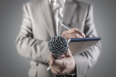 Bir basın konferansında ya da mikrofon tutan ve notlar yazan medya etkinliğinde gazeteci ya da haber muhabiri