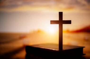 Dini haç, İncil 'in tepesinde günbatımı gökyüzü arka planı din, ibadet ve dua kavramı.