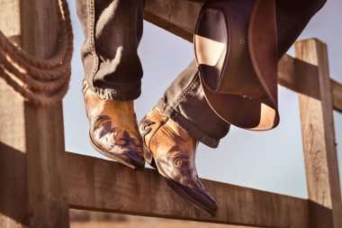 Çiftlik rodeosundaki çitlerde oturan kovboy çizmeleri ve şapkası dinleniyor, Country müzik festivali konser veya çizgi dansı konsepti