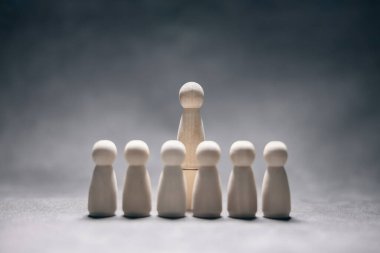 Liderlik sunumu konsepti, ahşap iş takımı ve kalabalıktan bir kişi öne çıkıyor.