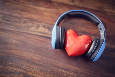 Müzik, kulaklık ve ahşap arka planda kırmızı kalp dinlemeyi seviyorum.