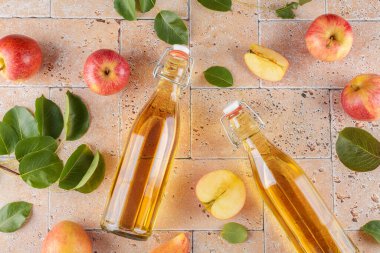 Elma sirkesi mayalanmış meyve iki cam şişe içinde taze organik kırmızı elmalar bej beton arka planda. Vitamin içeceği, sağlıklı beslenme tarzı, üst görünüm, düz yatak.