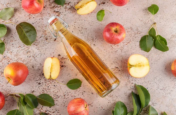 발효된 과일의 식초는 베이지 콘크리트 배경에 신선하게 사과가 유리병에 넣는다 — 스톡 사진
