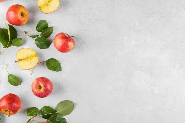 赤新鮮な有機リンゴを全体に熟し 薄い灰色のコンクリートテーブルの背景に緑の葉でスライスします テキスト トップビュー フレイレイレイのためのスペースを持つAppleバナー ストックフォト