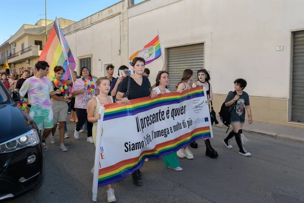 Manduria, İtalya - 13 Temmuz 2022. LGBTQ Onur Festivali 'ne katılan gençler pankartı İtalyanca: Şimdiki zaman tuhaf, biz alfa, omega ve çok daha fazlasıyız