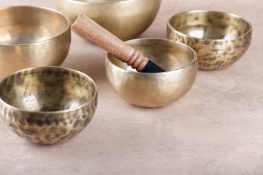 Bej taşından arka plan üzerinde yapılan meditasyonlarda kullanılan çubuklarla Tibet şarkı kaseleri, kopyalama alanı. Meditasyon, rahatlama, yoga, masaj ve akıl sağlığı için müzik aletleri