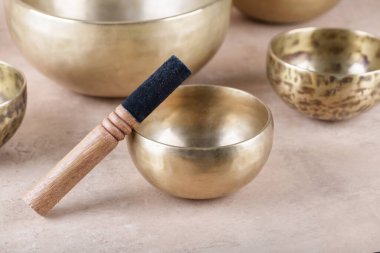 Bej taşından arka planda yapılan meditasyonlarda kullanılan sopalarla Tibet şarkı kaseleri, yakın çekim. Meditasyon, rahatlama, yoga, masaj ve akıl sağlığı için müzik aletleri