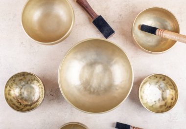 Bej taşından arka plan, üst manzara, düz yatış gibi mantra meditasyonlarda kullanılan sopayla Tibet şarkı kaseleri. Meditasyon, rahatlama, yoga, masaj ve akıl sağlığı için müzik aletleri