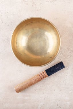 Tibet şarkı kasesi, bej taşından arka plan, üst manzara, düz yatış gibi mantra meditasyonlarda kullanılan sopayla. Meditasyon, rahatlama, yoga, masaj ve akıl sağlığı için müzik aletleri