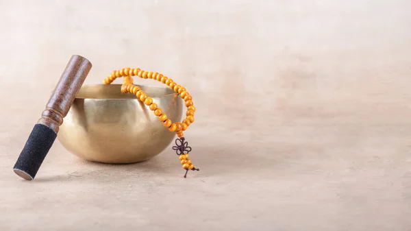 stock image Tibetan singing bowl with stick, mala beads strands used during mantra meditations on beige stone background. Sound healing music instruments for meditation, relaxation, yoga, massage, mental health