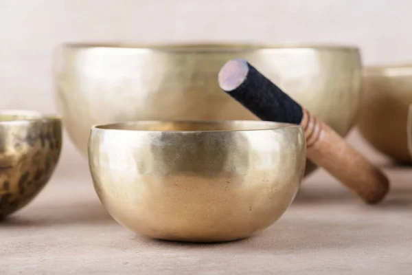 stock image Tibetan singing bowls with sticks used during mantra meditations on beige stone background, close up. Sound healing music instruments for meditation, relaxation, yoga, massage, mental health