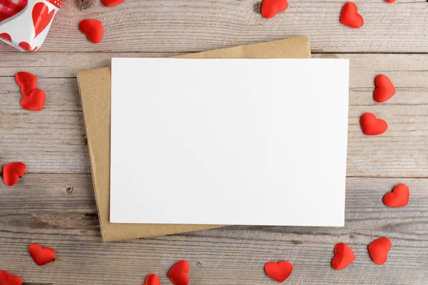 Blank wedding invitation stationery card mockup with envelope and red hearts on rustic wooden background. Valentines day card, valentines day background, Mothers day card, top view, flat lay