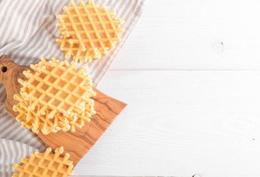 Ferratelle ya da pizzelle beyaz ahşap arka planda peçeteli kesme tahtasında geleneksel bir tatlı ya da kurabiye, fotokopi alanı, üst manzara. İtalya, Abruzzo 'nun bölgesel mutfağı. Meşhur waffle gibi.