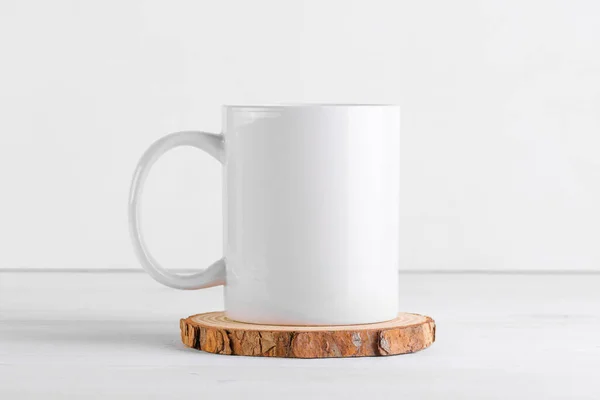 White mug mockup with blank copy space for your advertising text message or promotional content on a wooden podium on white background. Coffee mug mock up, close up