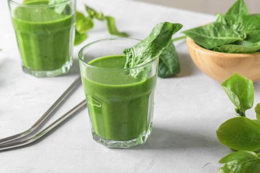 Ispanaklı, muzlu ve vejetaryen sütlü sağlıklı yeşil smoothie ve açık gri arka planda taze malzemeler. Detoks, diyet, sağlıklı, vejetaryen gıda konsepti, kapatın.