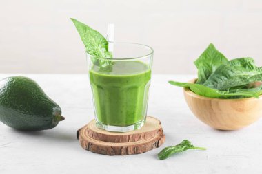 Sağlıklı yeşil smoothie, ıspanak, avokado, muz ve vejetaryen sütü ve açık gri arka planda taze malzemeler. Detoks, diyet, sağlıklı, vejetaryen gıda konsepti