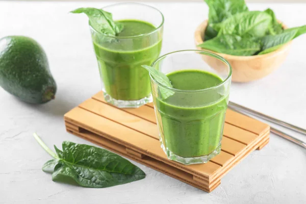 stock image Healthy green smoothie with spinach, avocado, banana, and vegan milk in two glasses and fresh ingredients on light grey table background. Detox, diet, healthy, vegetarian food concept
