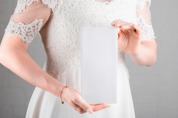Bride holding wedding menu card mockup on white wall background. Minimal stile blank mockup, thank you card, greeting card, wedding template