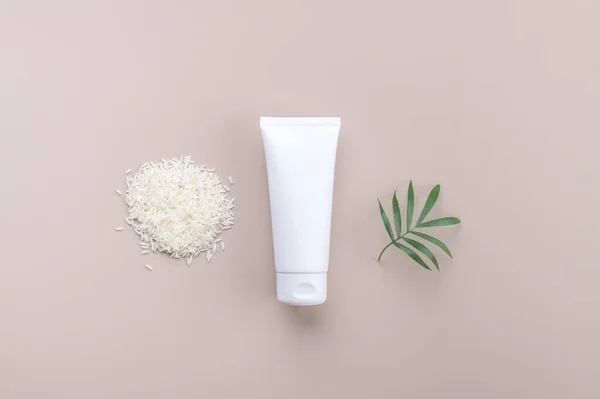 White squeeze bottle plastic tube mockup cosmetics with white rice on beige background. Skin care product body lotion, shampoo, face cream, gel or mask, Natural organic beauty cosmetics, top view