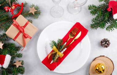 Doğal köknar dalları, Noel hediyesi ve açık gri masa zemininde altın çatal bıçak seti olan güzel bir Noel masası. Noel yemeği için şenlikli dekorasyon, düz yatak, üst manzara