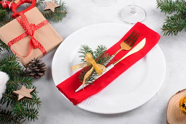 漂亮的圣诞餐桌布置 有着自然的冷杉枝条 圣诞礼物和浅灰色桌子背景的金色餐具 圣诞装饰品为圣诞晚餐配上节日装饰品 — 图库照片