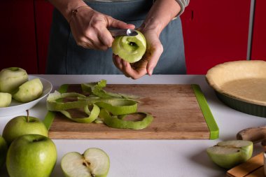 Kadın mutfakta elmalı turta hazırlamak için elma soyuyor. Otantik kadın elleri bir elmayı bıçakla soyarlar. Elmalı turta pişirme, adım adım tarif. Şükran Günü meyveli tart, sonbahar fırını.