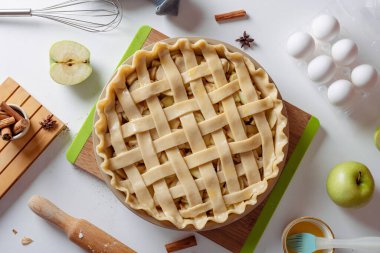 Pişmemiş elmalı turta, içinde malzemeler olan beyaz bir mutfak masasında pişirilmeye hazır. Ev yemeği konsepti, geleneksel Şükran Günü elmalı turta tarifi, yaşam tarzı, üst manzara.