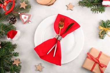 Doğal köknar dalları, Noel hediyesi ve açık gri masa zemininde altın çatal bıçak seti olan güzel bir Noel masası. Noel yemeği için şenlikli dekorasyon, düz yatak, üst manzara