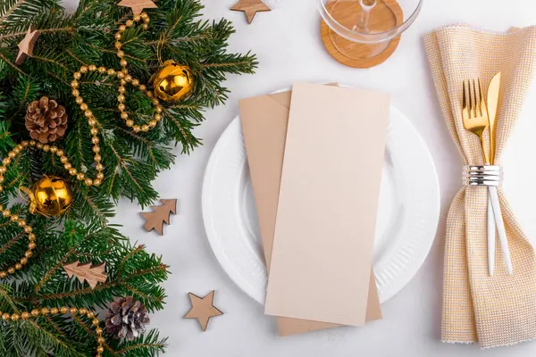 Christmas vertical menu card mockup with golden festive table setting with Christmas decoration on a natural fresh fir branch. Christmas menu or invitation card 4x9 ratio. Flat lay, top view