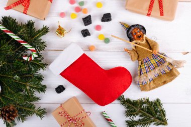 Cadı Befana ve beyaz ahşap arka planda tatlı kömür ve şekerli kırmızı çorap. İtalyan Epifani Günü geleneği, üst manzara, düz yatak, tebrik kartı