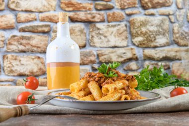 Özgün ev yapımı Bolognese ragu ve sade kahverengi masa arkaplanlı Rigatoni.