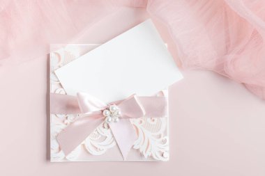 Beyaz düğün davetiyesi 7x5. Pastel pembe arka planda zarf ve kumaşla birlikte. Bebek partisi ve gelin duşu modeli. Asgari biçim boş model, teşekkür kartı, tebrik kartı