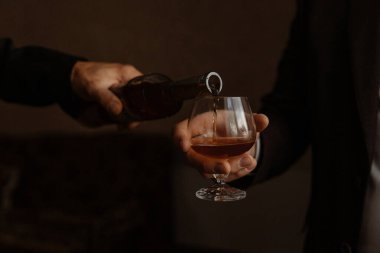 the man pours some brandy into a glass behind the bar clipart