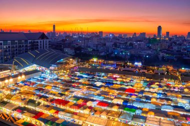 Bangkok, Tayland ve renkli gece pazarının ufuk çizgisi üzerinde güzel bir günbatımı. Günbatımından sonra Asya pazarı kaosu, çok renkli çadırlar, gıda tezgahları, barlar ve restoranlar, şehir hayatı, pazar yeri, turist