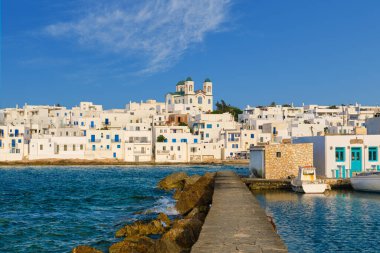 Yunanistan 'ın güneşli bir günde, Naoussa, Paros Adası, Yunanistan' da, deniz kenarındaki tepenin yerel simgesi olarak, beyazlatılmış geleneksel Yunan evleri ve Tanrı 'nın Annesi Dormition kilisesi bulunmaktadır. Limanda demirlemiş rıhtım ve tekneler