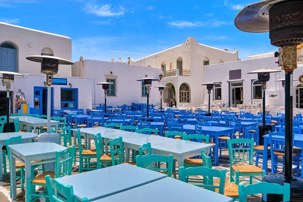 stock image Seafood restaurants, cafes and bars in Naoussa bay, colorful tables and chairs, whitewashed houses on sunny summer day. Traditional Greek cuisine, Mediterranean fresh food, vacations, travel