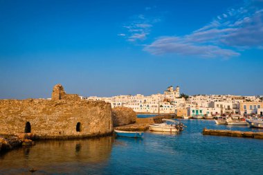 Yunanistan 'ın güneşli bir günde, Naoussa, Paros Adası, Yunanistan' da, deniz kenarındaki tepenin yerel simgesi olarak, beyazlatılmış geleneksel Yunan evleri ve Tanrı 'nın Annesi Dormition kilisesi bulunmaktadır. Venedik şatosu kalıntıları, tekneler, rıhtım.