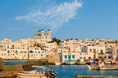 Yunanistan 'ın güneşli bir günde, Naoussa, Paros Adası, Yunanistan' da, deniz kenarındaki tepenin yerel simgesi olarak, beyazlatılmış geleneksel Yunan evleri ve Tanrı 'nın Annesi Dormition kilisesi bulunmaktadır. Limanda demirlemiş rıhtım ve tekneler