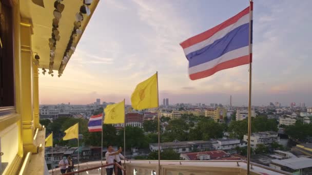 バンコク 2020年1月2日 タイの寺院の観光客がセルフィーを取っています 黄金の葉 黄金の壁 タイの国旗とタイの王国旗が強風とバンコクで揺れている仏教鐘 — ストック動画