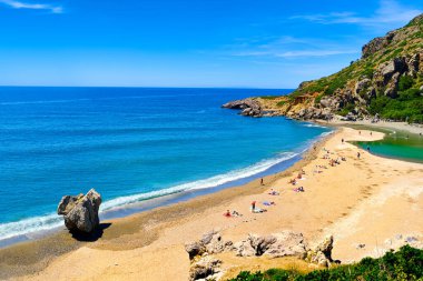 Yunanistan 'ın Preveli, Girit Adası' ndaki kumlu sahil manzarası güneşli bir günde. Seyahat güzergahı, nehir ve berrak Libya deniz suları, orman, palmiye ağaçları, vadi, bulutlu mavi gökyüzü. Turist yüzüşü ve